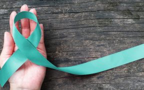 Teal ribbon awareness on woman's hand for Ovarian Cancer, Polycystic Ovary Syndrome (PCOS) disease, Post Traumatic Stress Disorder (PTSD), Tourette's Syndrome, Obsessive Compulsive Disorder (OCD)