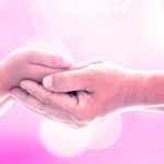an image of two people, one person's hands cupping the other, with a pink background