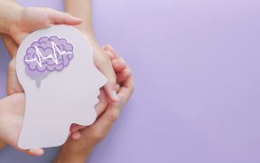 a light purple background. On the left, a group of white hands are stacked on top of each other face up, and on top is a cutout of a person's head with the brain shown