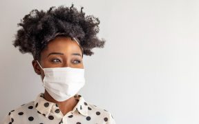 a photo of a Black woman in a mask looking to the right