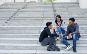 a photo of three teens sitting on a group of step