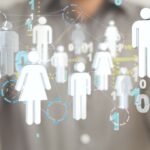 a man in a grey shirt, hands apart, and between the hands are graphics of the people icon both men and women