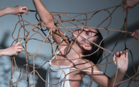 a young woman in a dancer outfit is underneath a rope net