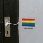 a door with he LGBT flag next to it