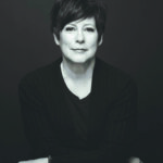 a black and white photo of a white woman with dark hair wearing a black top